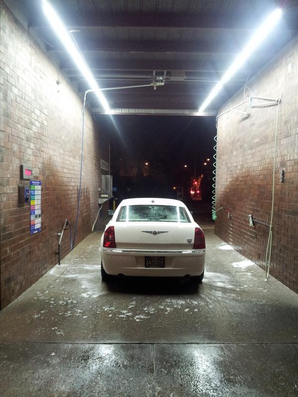 Hi Performance Car Wash bay illuminated by bright LED lights at night, wet concrete gleaming